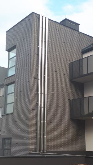 3 kominy stalowe mocowane na elewacji budynku wielorodzinnego